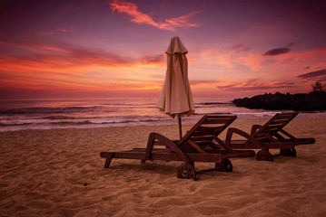 Sea sunrise view with two deck chairs and a beach umbrella