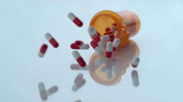 Pills spilling out of bottle in slow motion