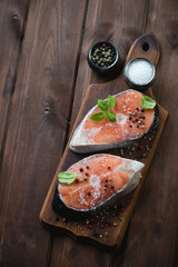 Top view of raw salmon steaks with spices, rustic wooden surface