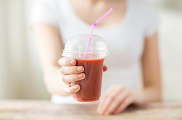close up of woman holding cup with smoothie