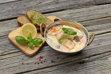 Fish soup in metal plate on wood