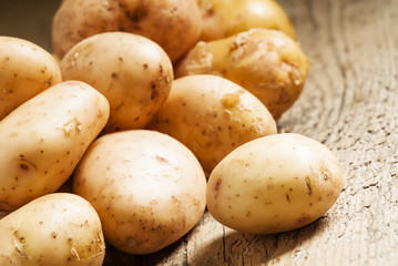 Fresh potatoes in an old wooden table, selective focus