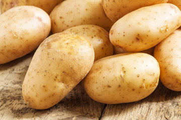 Fresh potatoes in an old wooden table, selective focus