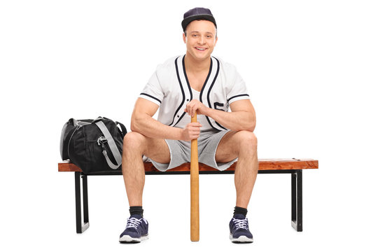 Baseball player sitting on bench and holding a bat