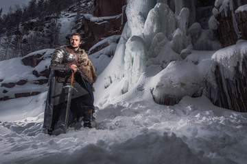 Medieval knight with sword in armor in winter landscape