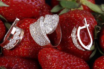 Beautiful gold ring and earrings with small diamonds on a red strawberry.