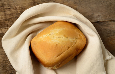 Loaf of bread on the linen napkin,   wooden background