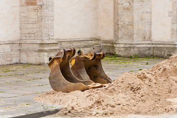 Zwei Tieflöffel liegen neben einem Sandhaufen