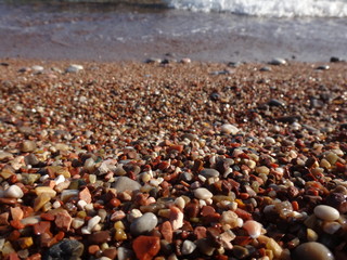 Цветная мелкая галька на пляже, освещенная солнцем