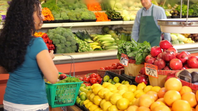 Grocery store worker helps woman shopping for produce