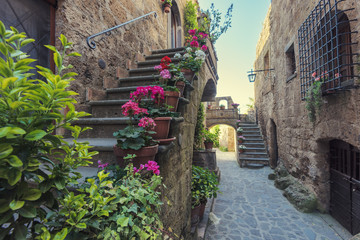 Fototapeta premium Schody z kolorowymi kwiatami w toskańskim starym mieście