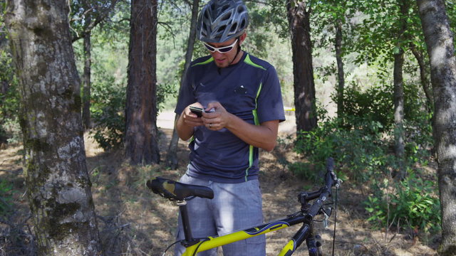 Mountain biker takes a break to check cell phone