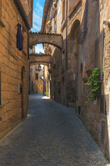 Italian streets with arches on a sunny day and long shadows