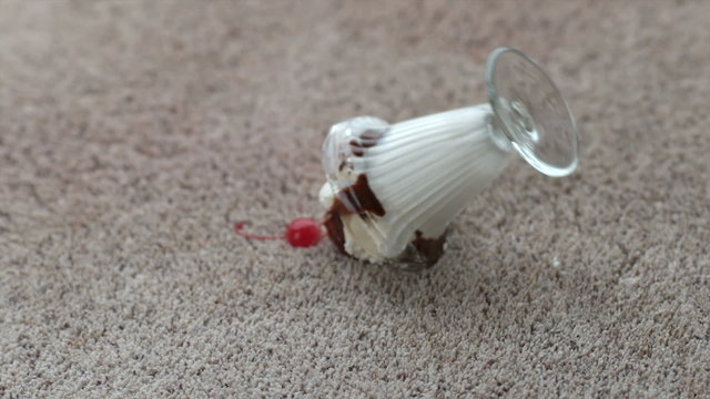 Ice cream sundae spilling on carpet in slow motion