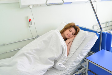 Female patient lying on  bed in hospital ward