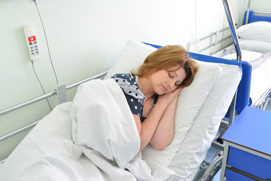 Female Patient Lying On Bed In Hospital Ward