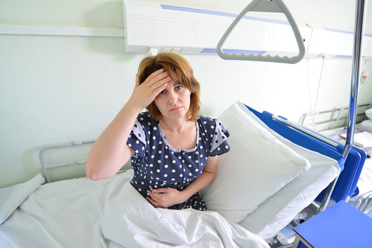 Female patient with headache on  bed in hospital ward