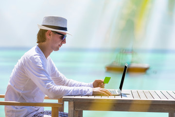 Young man with tablet computer on tropical beach