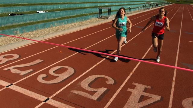 Track runner crosses finish line, slow motion