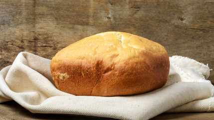 Loaf of bread on the linen napkin,   wooden background