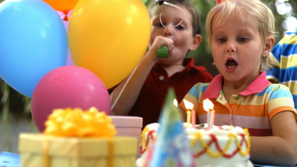 Young girl blowing out birthday candles - Powered by Adobe
