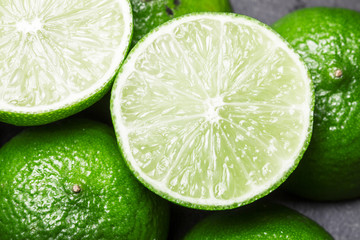 Fresh limes cut in half on black surface