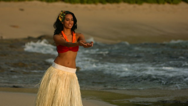 Polynesian hula dancer performs by ocean, slow motion