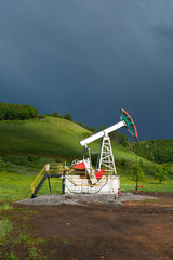 Fototapeta na wymiar Pumping unit for pumping oil on a dark blue storm clouds