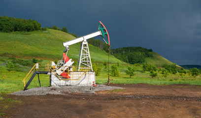 Fototapeta na wymiar Pumping unit for pumping oil on a dark blue storm clouds