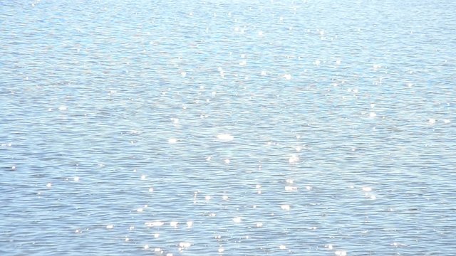 Light blue water surface glittering in the sun with sparkles