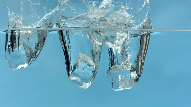 Ice cubes dropping into water slow motion