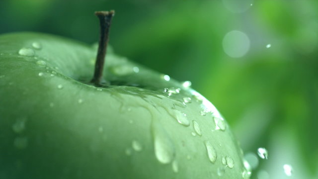 Extreme close-up of water drip on apple in slow motion
