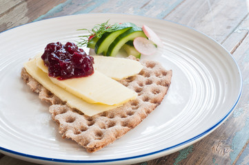 Scandinavian crisp bread topped with cheese and lingonerry jam served with a salad of cucumber, radish and dill.