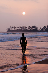 Woman walking on beach at sunset