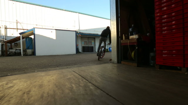 BMX rider doing tricks in warehouse.