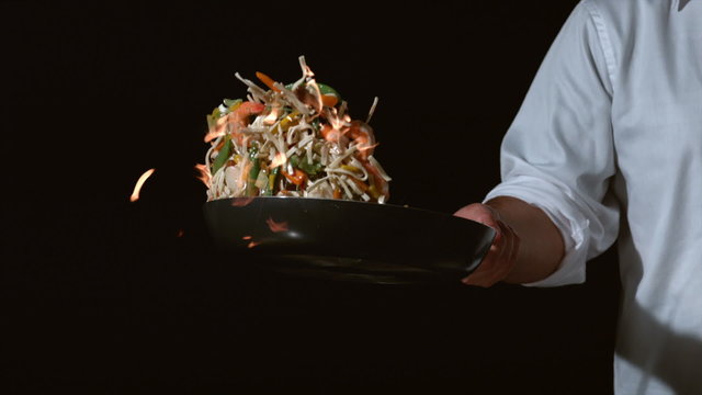 Slow motion shot of chef with flaming stir fry