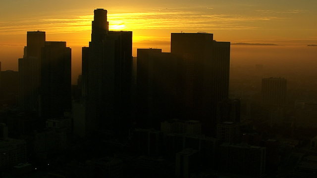 Aerial view of silhouetted Los Angeles skyscrapers at sunrise