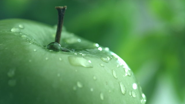 Extreme close-up of water drip on apple in slow motion