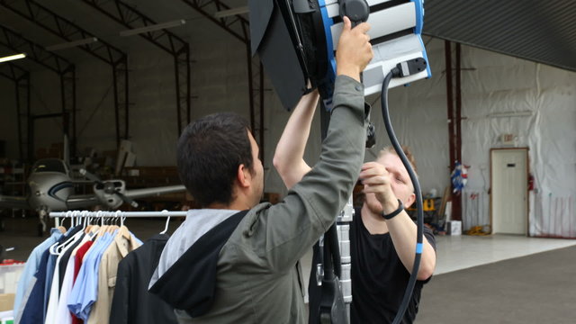 Behind the scenes two men on movie set put up light
