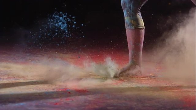 Foot hitting colored powder as girl runs, slow motion
