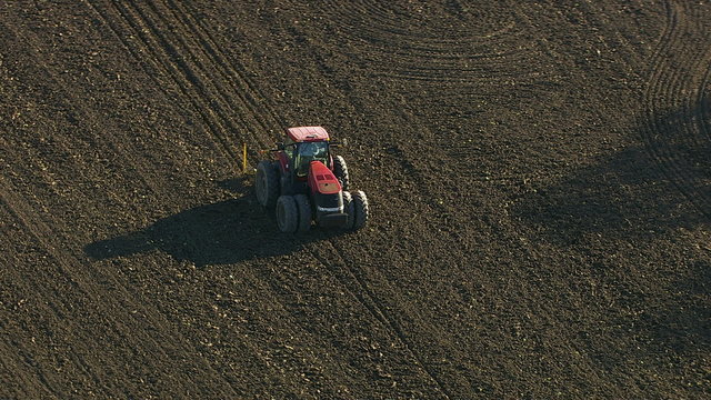 Agriculture, aerial shot of tractor plowing field