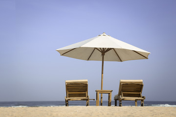 Tropical beach scenery with parasol and chairs 