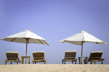 Tropical beach scenery with white parasols and chairs