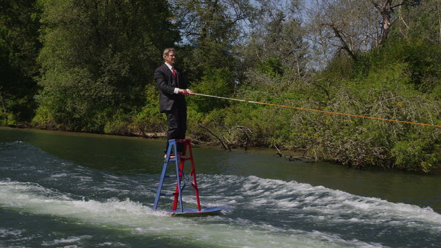 Businessman water skiing on ladder