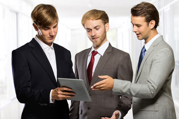 Three young businessman discussion about a something on a tablet
