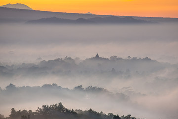 Fototapeta premium Colorful sunrise over Borobudur temple in misty jungle forest, I