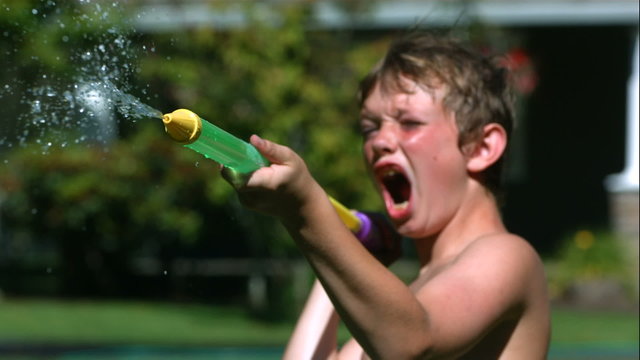 Two young boys having squirt gun fight in slow motion