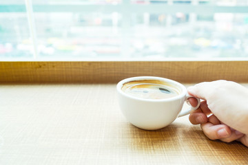 woman hand holding Espresso Coffee cup on wood table in cafe wit