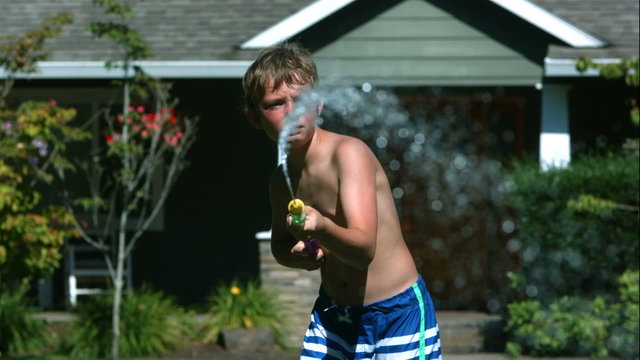 Two young boys having squirt gun fight in slow motion