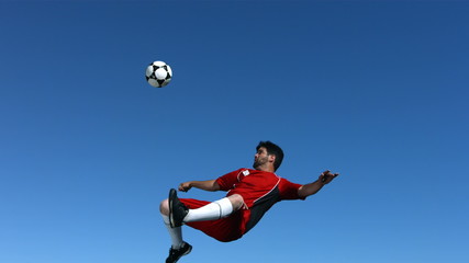 Soccer player kicking ball in mid-air, slow motion - Powered by Adobe